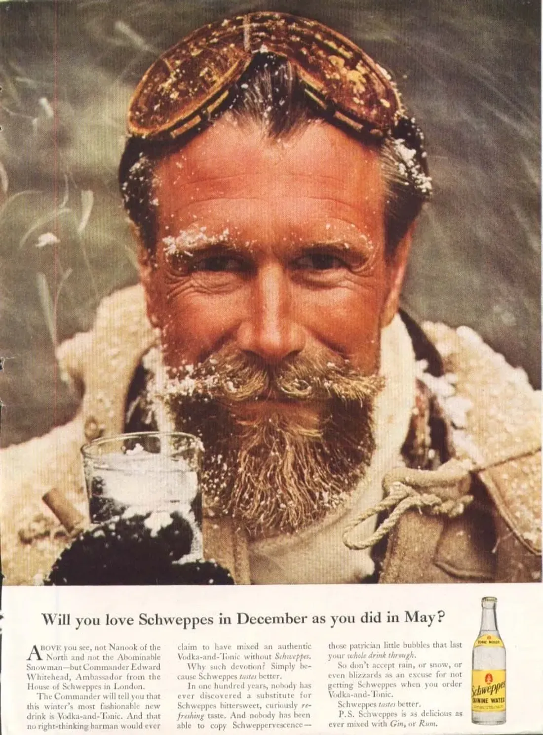 Ritratto del Commander Edward Whitehead, con barba e occhiali da sci, un bicchiere di Schweppes in mano