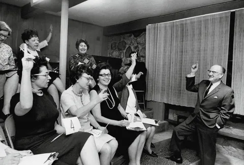 Fotografia d'epoca di un panel di giudici, in maggioranza donne, che alza la mano per votare durante una sessione di ricerca di mercato: il tipo di osservazione da cui nasce un insight.
